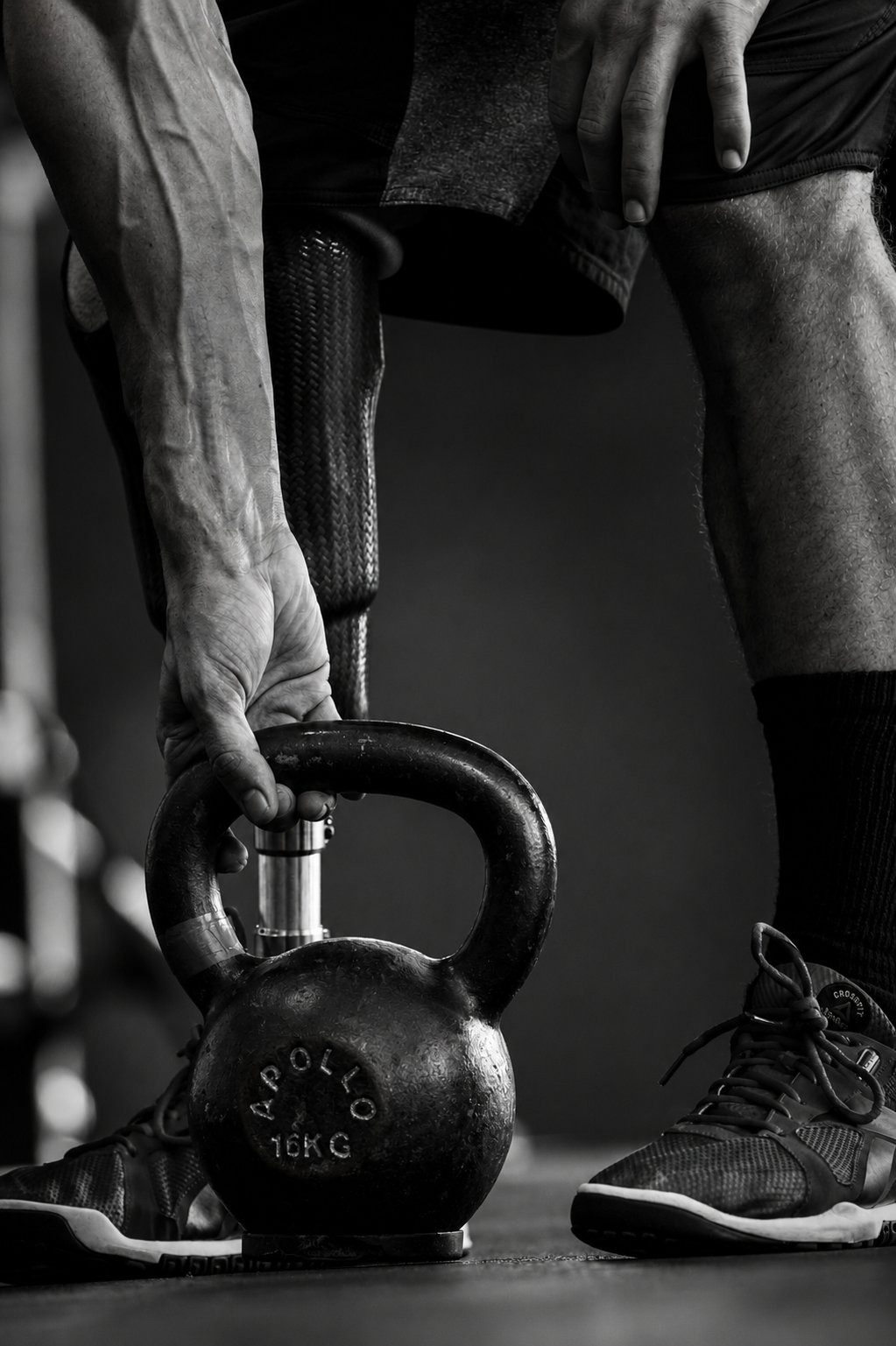 Černobílý detail sportovce zvedajícího kettlebell 16 kg